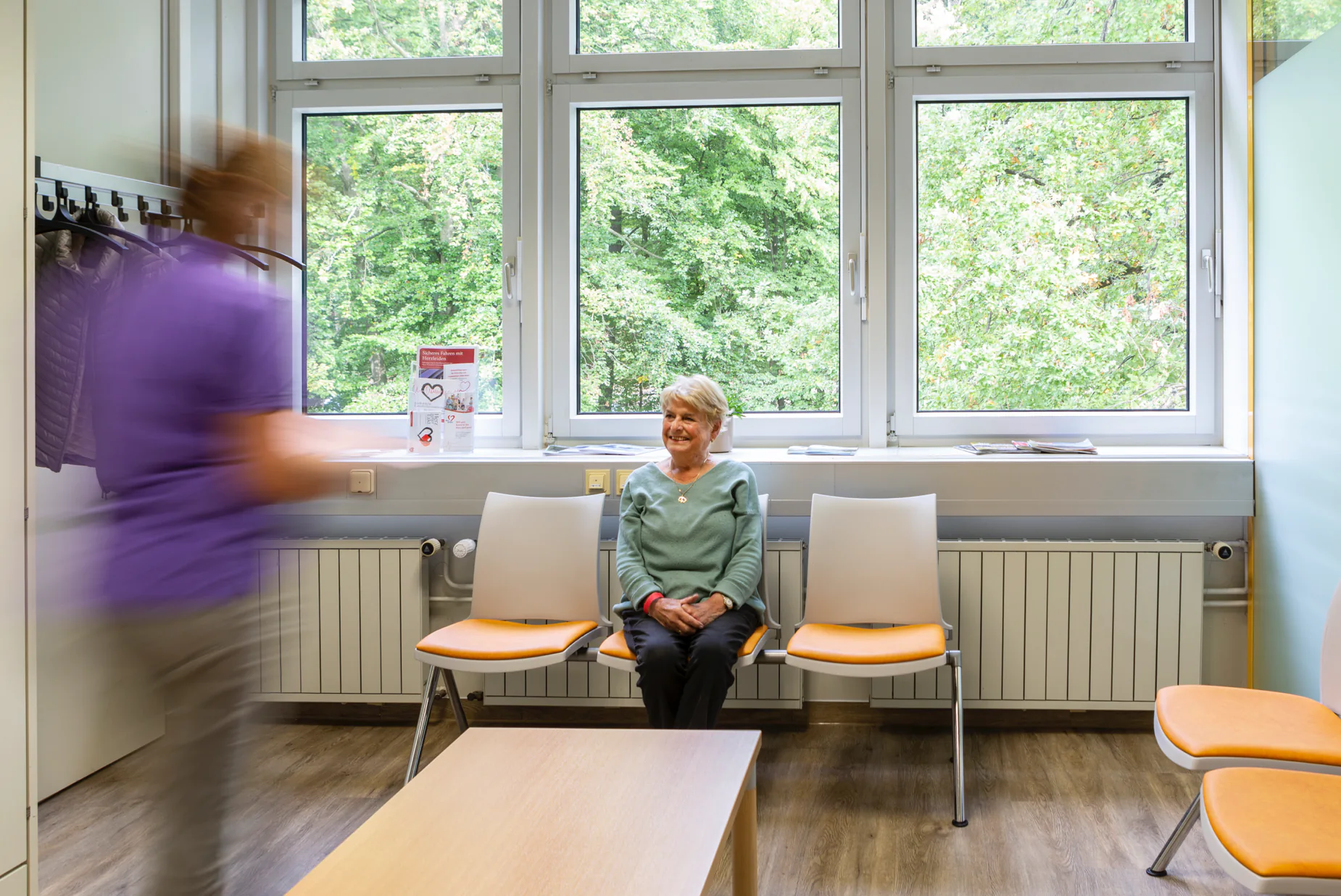 Eine Patientin wird in einem Wartezimmer von MFA aufgerufen